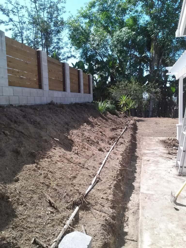 Backyard landscape construction with drainage pipe for erosion control.