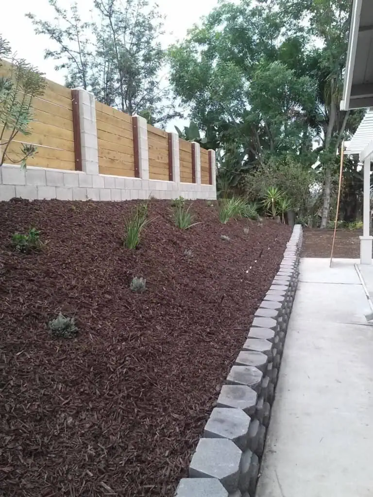 Ensuring functional and aesthetic yard space with durable retaining wall, mulch, and decorative border stones.