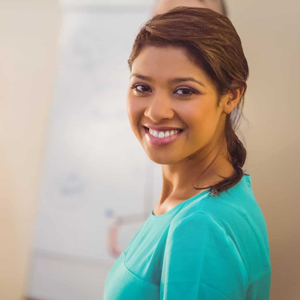 Smiling woman in turquoise scrubs, professional landscape services, outdoor garden design.